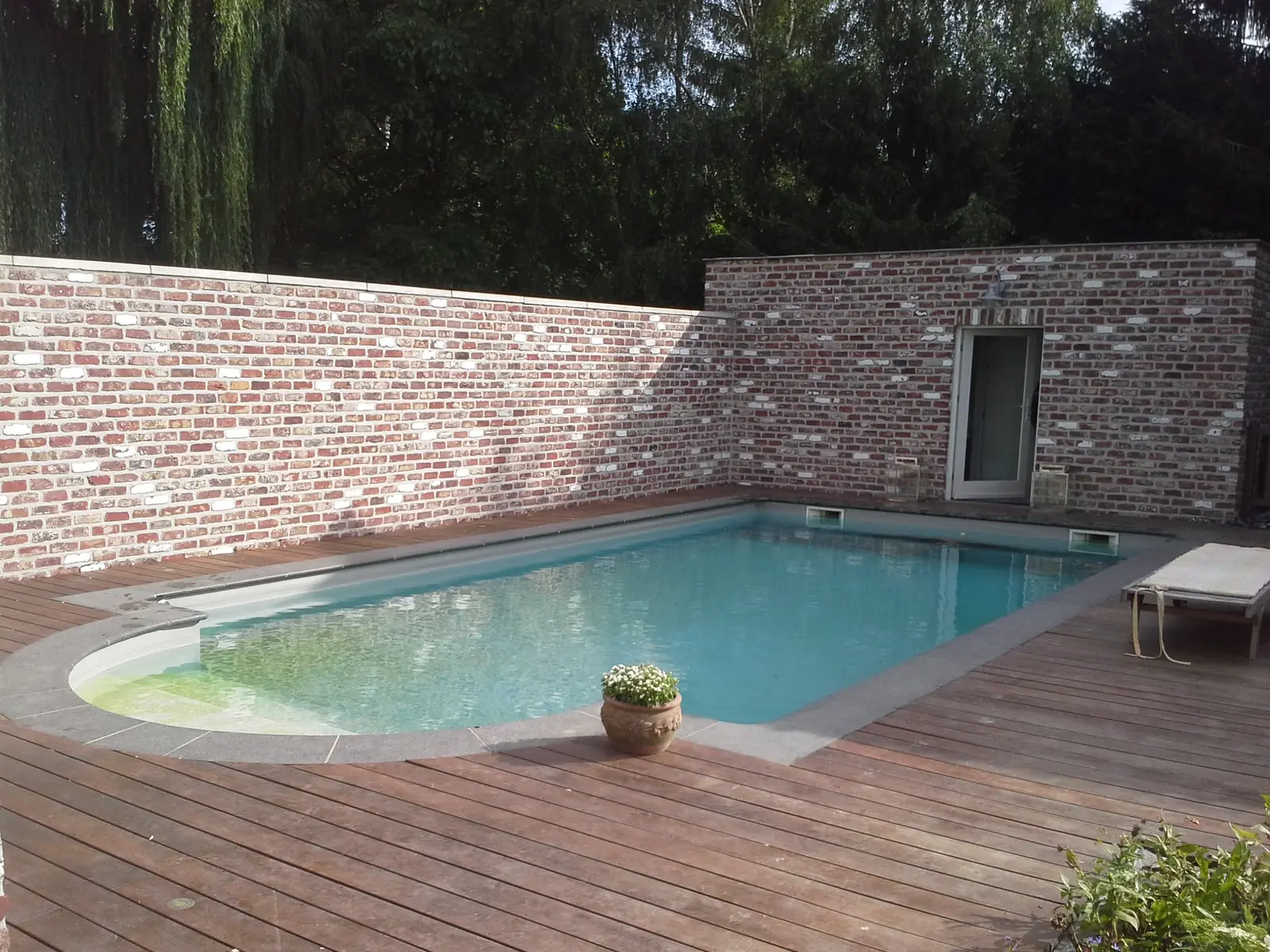 Zwembad met houten terras en tuinmuur (foto 1 van 2)